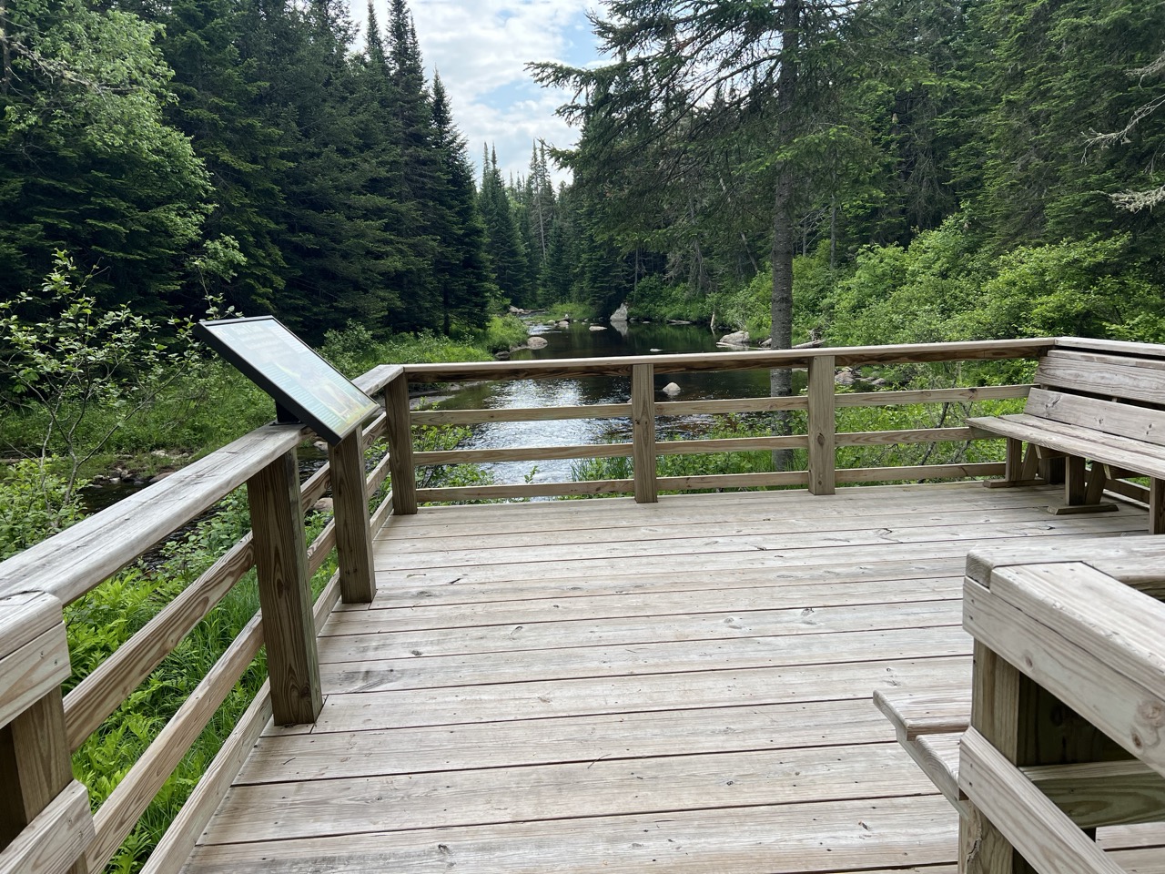 Large viewing platform with info panel overlooking river.